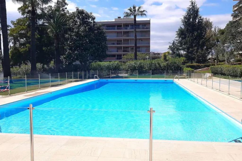 une grande piscine bleue avec un bâtiment en arrière-plan dans l'établissement Luxueux Appartement 3 pièces, à Antibes