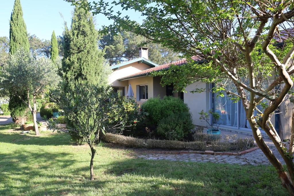 une maison blanche avec des arbres dans la cour dans l'établissement Villa dans un cadre de verdure 110 m2 proche Golf et Lac, à Soorts-Hossegor