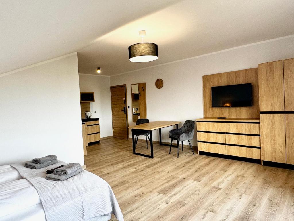 una habitación con una cama y una mesa y un televisor en Apartamenty Flauta, en Jastrzębia Góra