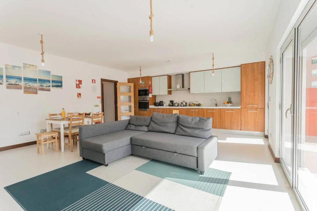 Una sala de estar con un sofá y una cocina. en Lovely & New BEACH APARTMENT, en Atouguia da Baleia
