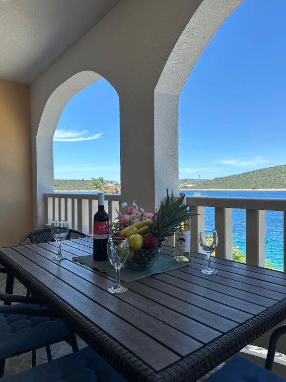a wooden table with wine glasses and fruit on a balcony at Apartman Majba 2 in Zaglavice