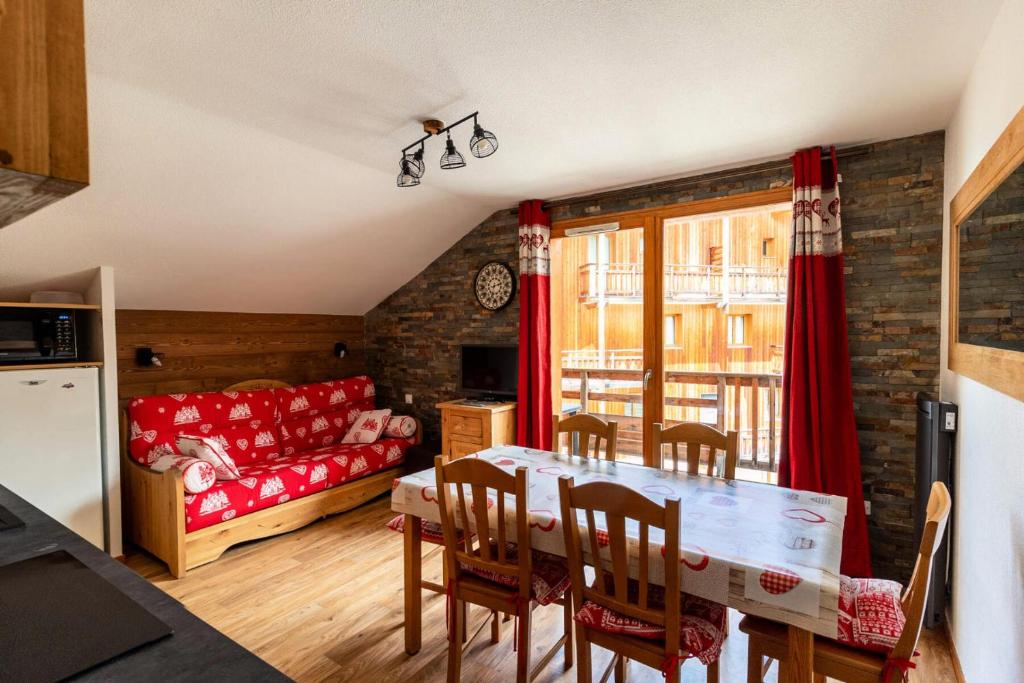 un salon avec une table et un canapé rouge dans l'établissement Les Chalets De Bois MÉan - C - Magnifique appartement montagnard aux Orres 1800 MAE-6531, aux Orres