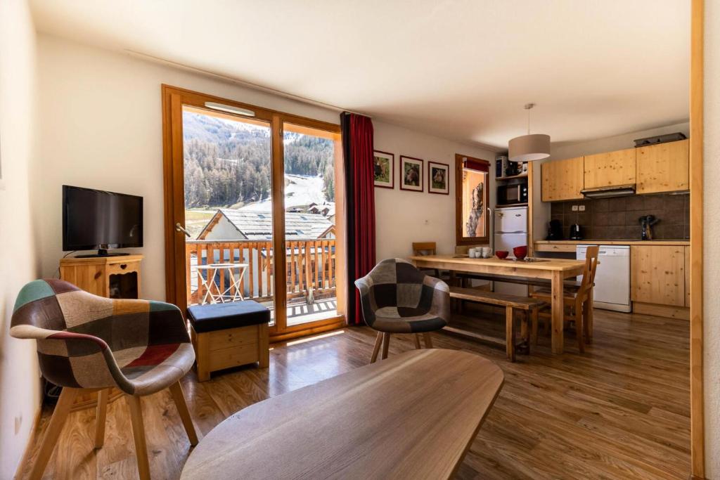 un salon avec une table et des chaises et une cuisine dans l'établissement Les Chalets De Bois MÉan - A - Magnifique appartement montagnard aux Orres 1800 MAE-6521, aux Orres