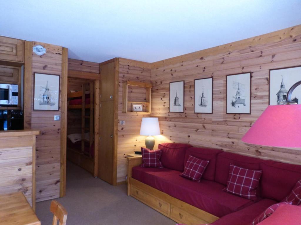 - un salon avec un canapé rouge et des murs en bois dans l'établissement Résidence Les Dauphinelles - Agréable studio à Méribel Altiport proche des pistes MAE-7641, à Les Allues