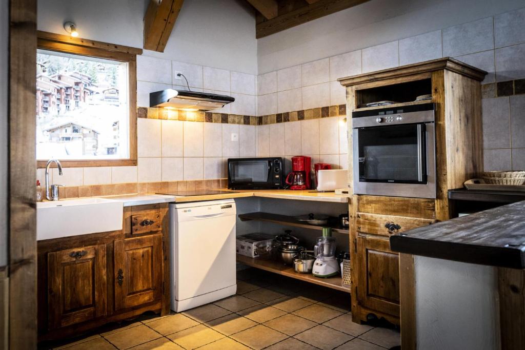 une cuisine avec des armoires en bois et un réfrigérateur blanc dans l'établissement Les Chalets Du Cocoon - CHALET PIERRA MENTA 1 MAE-1641, à Aime La Plagne