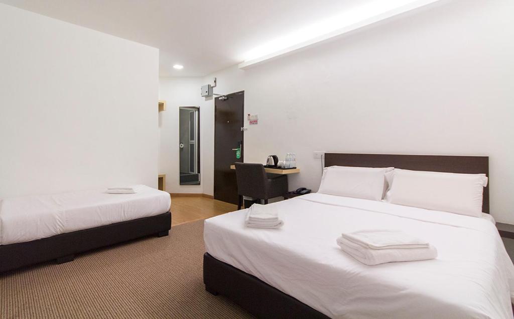 a bedroom with two beds with white sheets and a desk at HOTEL RAUB since 1968 in Raub