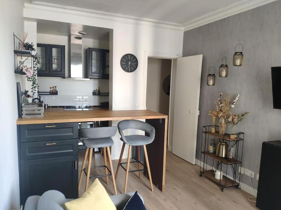 une cuisine avec un comptoir et des tabourets dans une pièce dans l'établissement Charmant deux pièces moderne, à Saint-Ouen