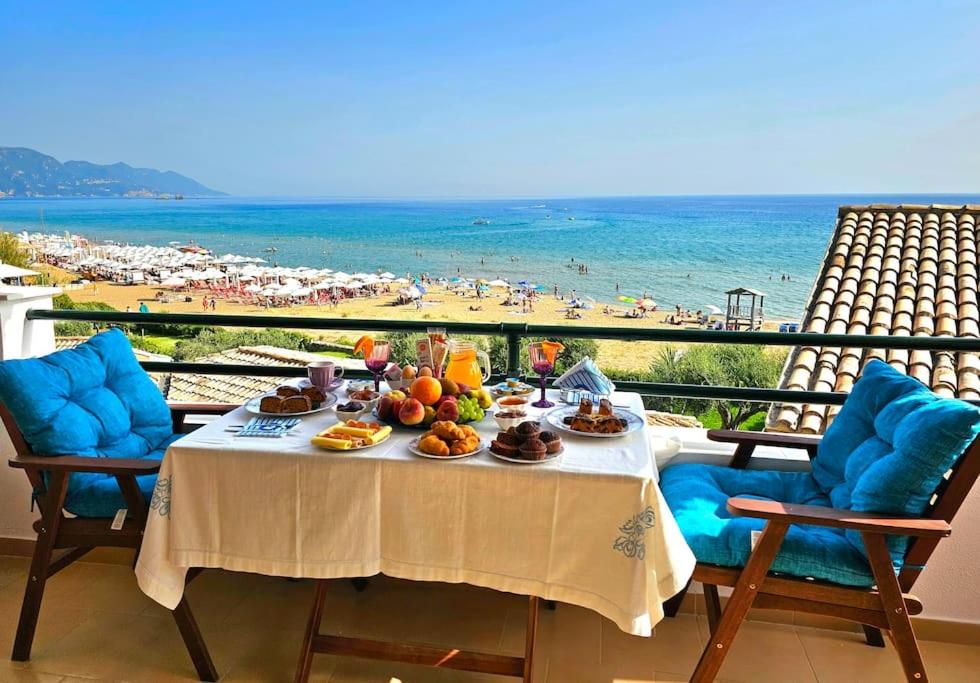 a table with food and a view of a beach at Breeze Beach Apartment Glyfada in Corfu