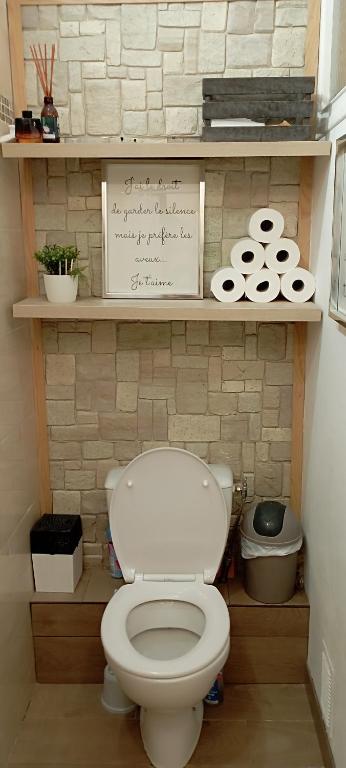 une salle de bain avec des toilettes blanches et un panneau sur une étagère dans l'établissement Appartement 4 couchages, à Corte