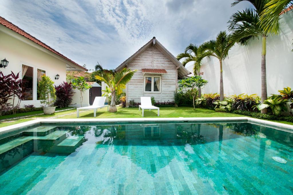a villa with a swimming pool in front of a house at Green Garden Seminyak Villa in Seminyak