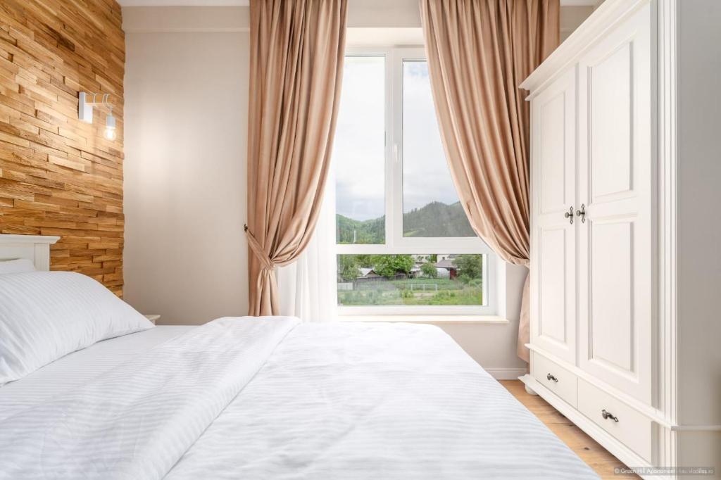 Un dormitorio con una cama blanca y una ventana. en GreenHill Apartament, en Gura Humorului