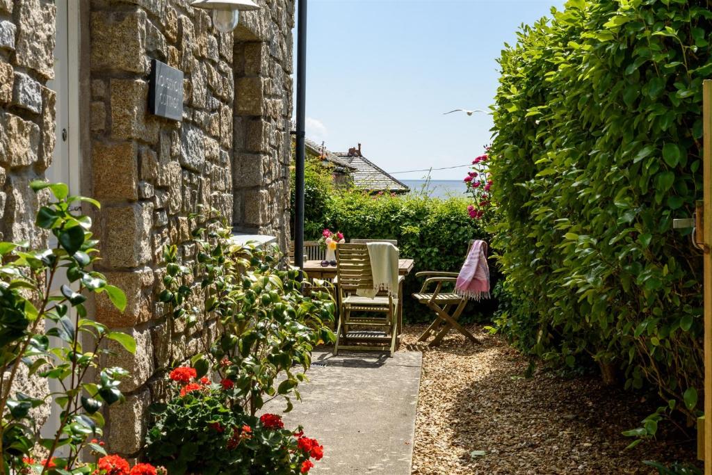 a garden entrance to a house with a table and chairs at Mousehole Cottage in Penzance