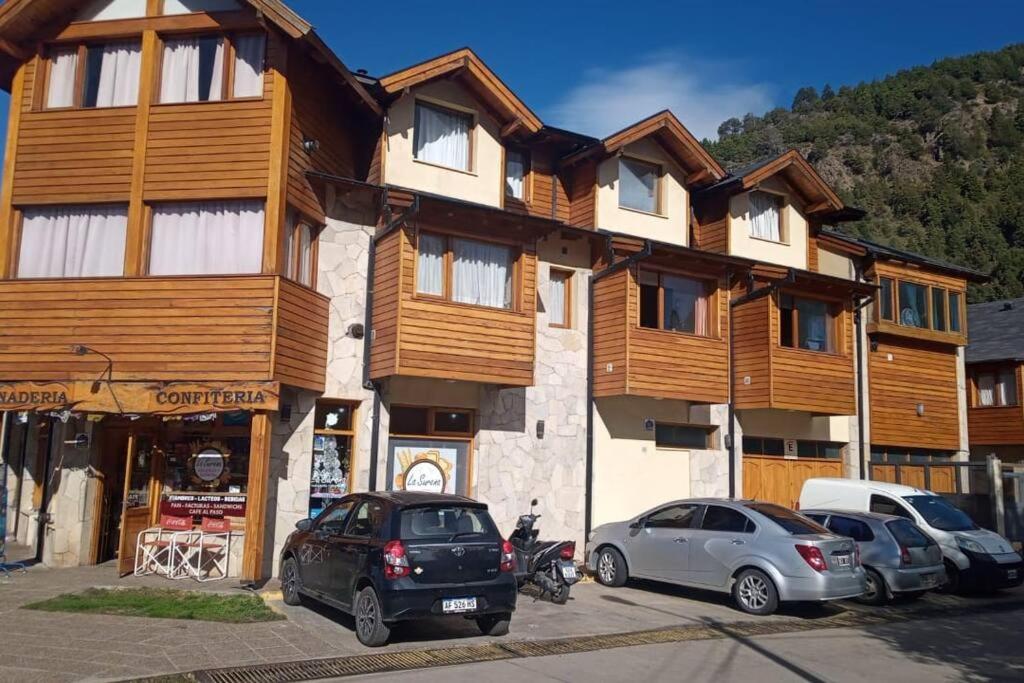 a building with cars parked in front of it at Cabaña acogedora y cómoda en el centro de la ciudad in San Martín de los Andes