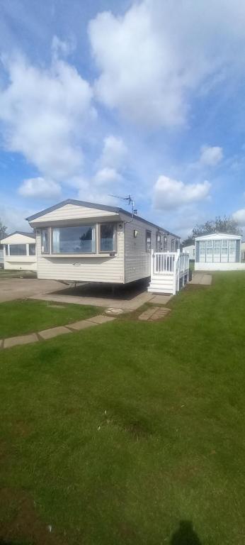 a house with a large yard with a green lawn at Tunstall J&D Caravan on the East Coast in Tunstall