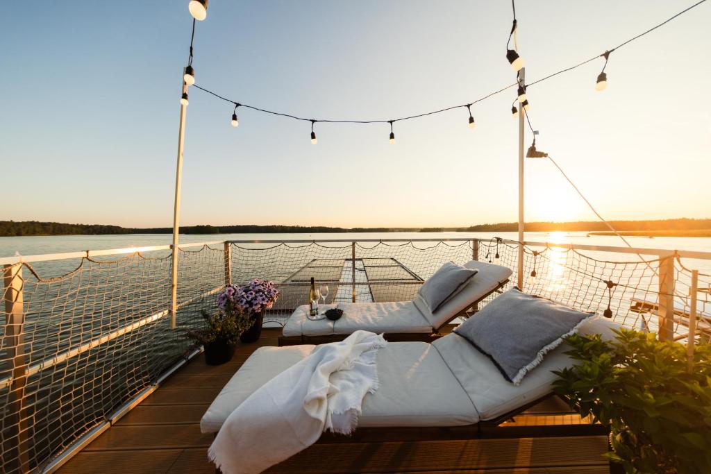 una terraza con 2 sillas y una mesa en un barco en Domek na wodzie - Houseboat -sauna, taras na dachu, dwie sypialnie, en Mikołajki