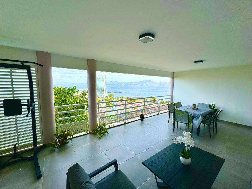 a living room with a table and a view of the ocean at Escapade Panoramique Appt prestige vue mer in Fort-de-France
