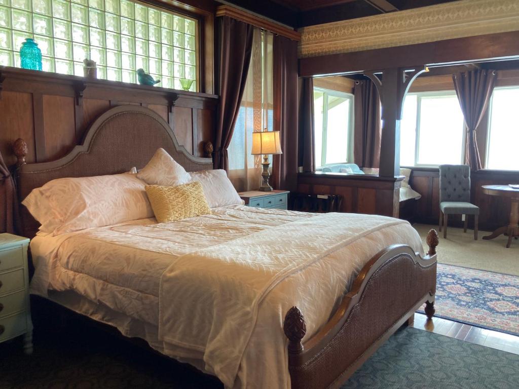 una camera con un grande letto in una stanza con finestre di Hilo Bay Oceanfront Bed and Breakfast a Hilo