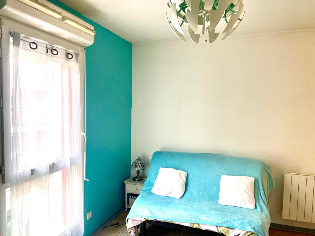 Cette chambre bleue comprend un lit et un lustre. dans l'établissement Studio et box 2 arrêts tram Partdieu, 4 du Groupama Stadium avec le tramway T3, à Villeurbanne