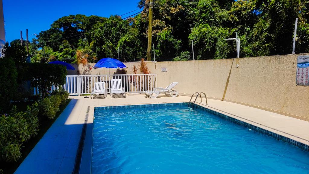 a swimming pool with two chairs and an umbrella at Confortável apartamento perto de praias - Bertioga in Bertioga