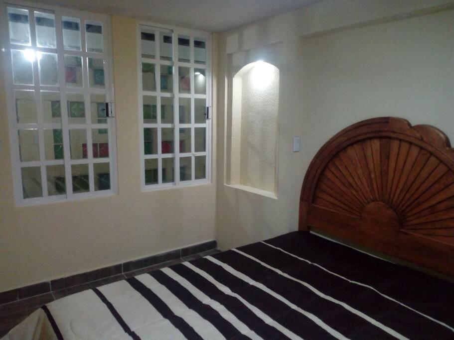 a bedroom with a wooden bed and a window at Departamento céntrico 10 minutos aeropuerto CDMX in Ciudad Nezahualcóyotl