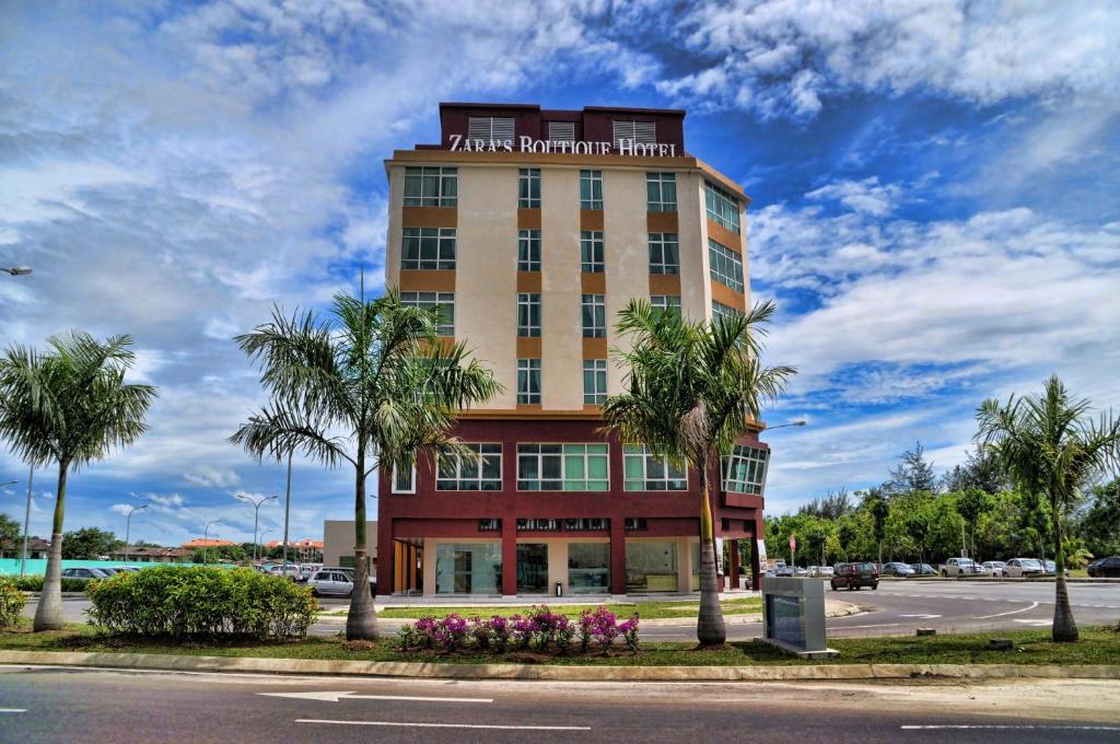 a tall building with palm trees in front of a street at Zara's Boutique Hotel @ Harbour City in Kota Kinabalu