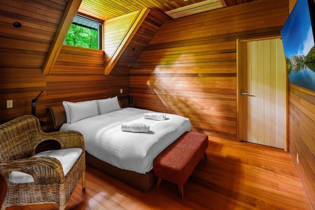a bedroom with a bed in a room with wooden walls at Phoenix Chalets by HHG in Hakuba