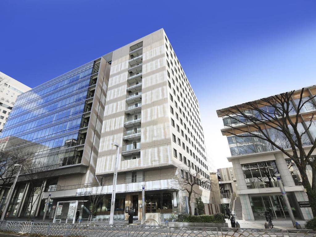 a tall white building with windows on a street at Richmond Hotel Nagoya Nayabashi in Nagoya