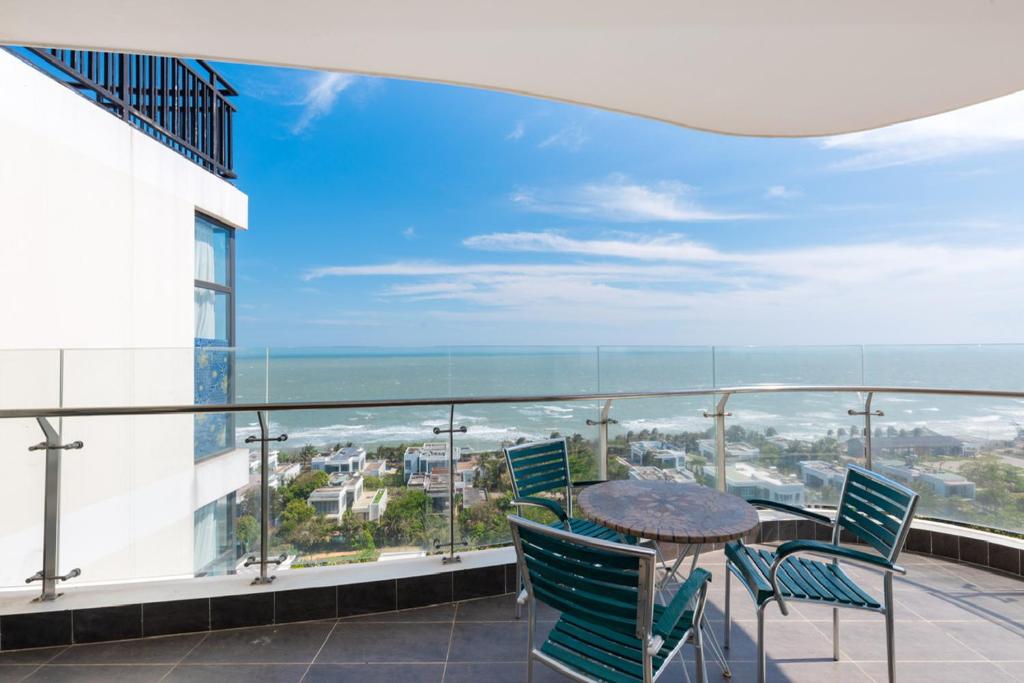 un balcon avec une table et des chaises et l'océan dans l'établissement ARIA Vũng Tàu - Thành Phố Vũng Tàu, à Xã Thắng Nhứt