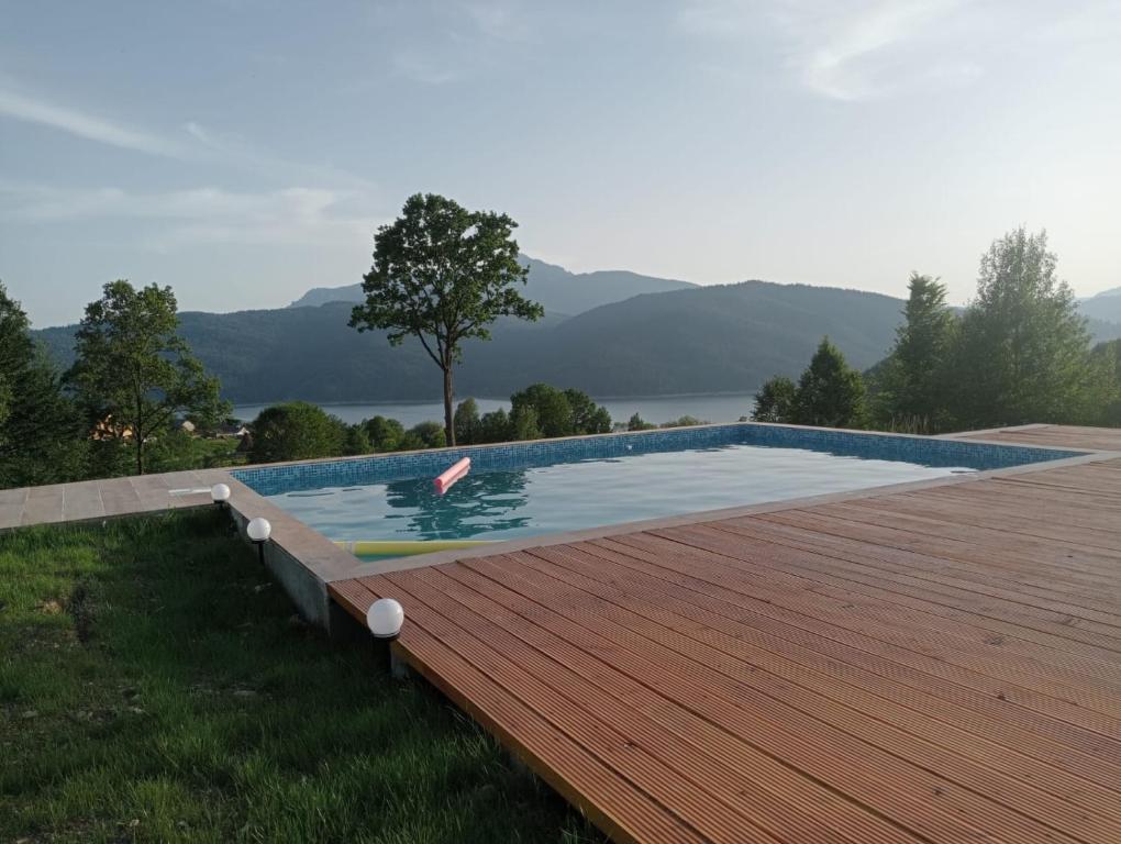 a swimming pool on top of a wooden deck at Perfect view cottage with pool in Buhalniţa