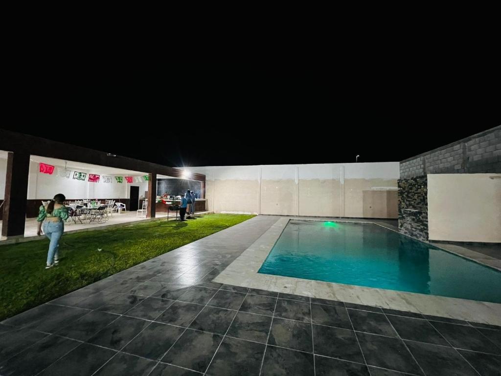 Eine Frau, die nachts neben einem Schwimmbad steht. in der Unterkunft quinta la gaviota in Gómez Palacio