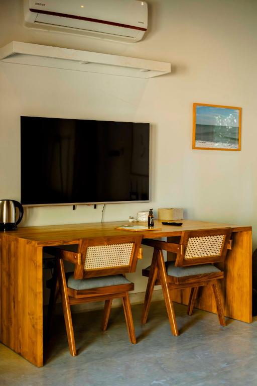 a living room with a table and a large screen television at The Spice Trail in Arugam Bay