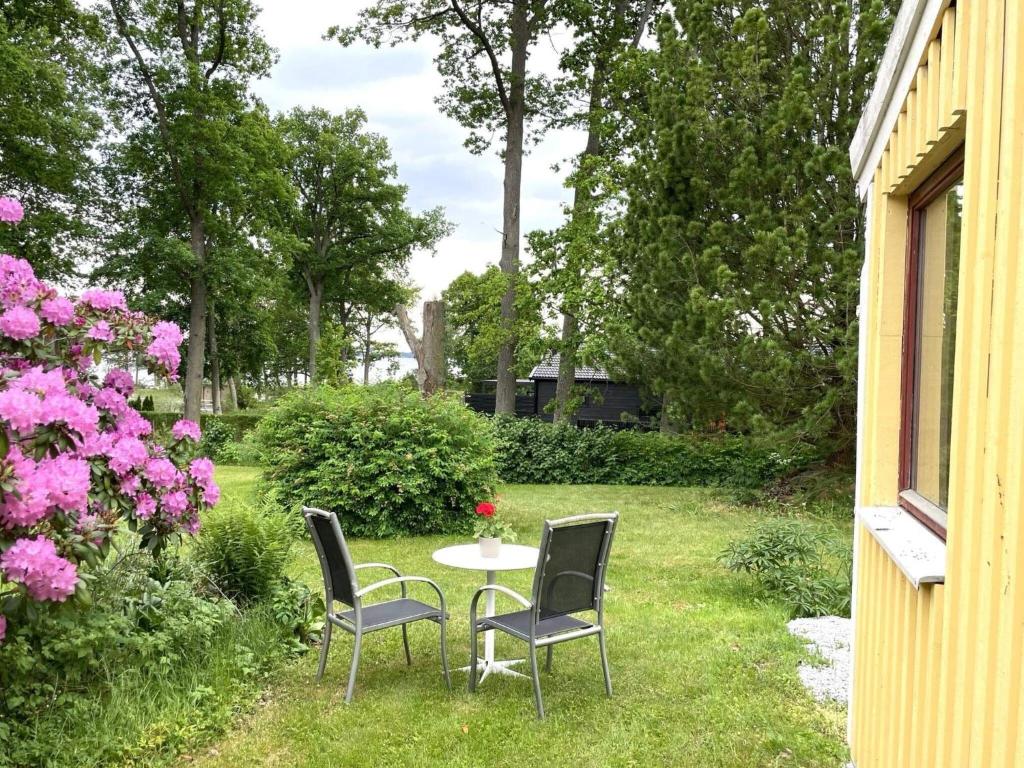 two chairs and a table in a yard with flowers at 2 person holiday home in NORRKÖPING in Norrköping