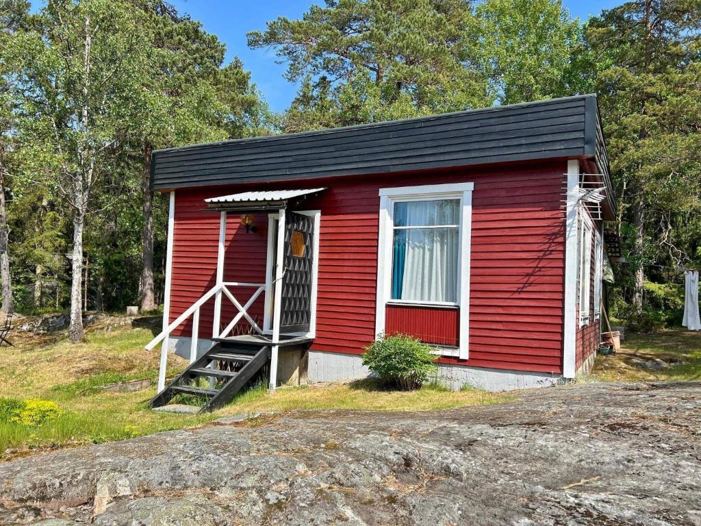 a red tiny house with a porch and a door at 6 person holiday home in Djurhamn in Djurhamn
