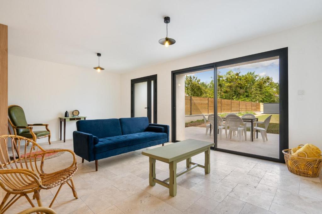 un salon avec un canapé bleu et une table dans l'établissement La maison du Sophora grande maison 3 chambres, à Saint-Didier-de-Formans
