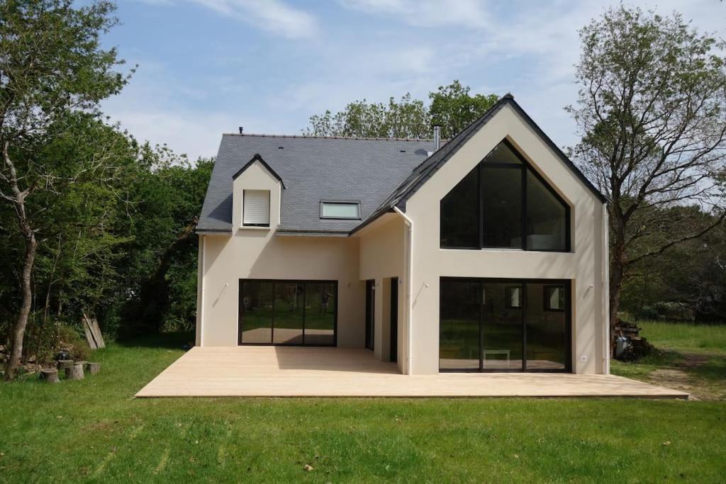 une maison avec de grandes fenêtres sur un champ vert dans l'établissement Carnac au calme, en pleine foret à 400 m d'un bras de mer, à Carnac