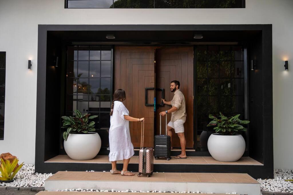 a man and a woman standing outside a door with a suitcase at Heaven Retreat with Minigolf, pool, fire pit, BBQ in Nadi