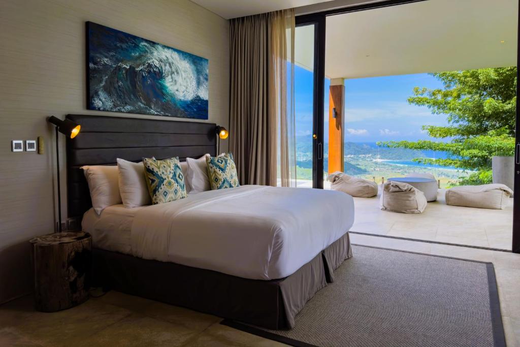 a bedroom with a large bed and a large window at Selong Selo Resort and Residences in Selong Belanak