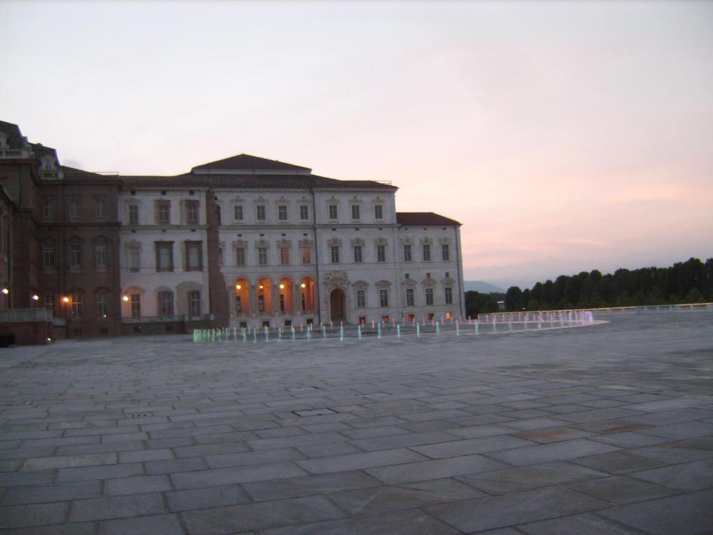 un grande edificio bianco con un tramonto sullo sfondo di Monolocale Dormire alla Reggia a Venaria Reale