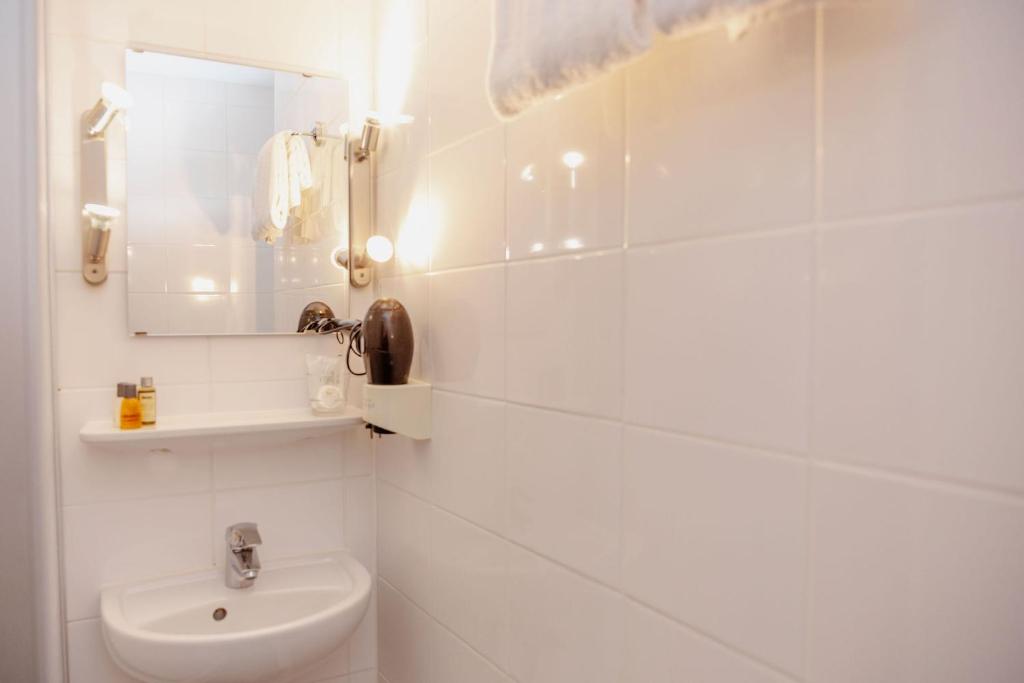 a white bathroom with a toilet and a mirror at Hotel Lux in Munich