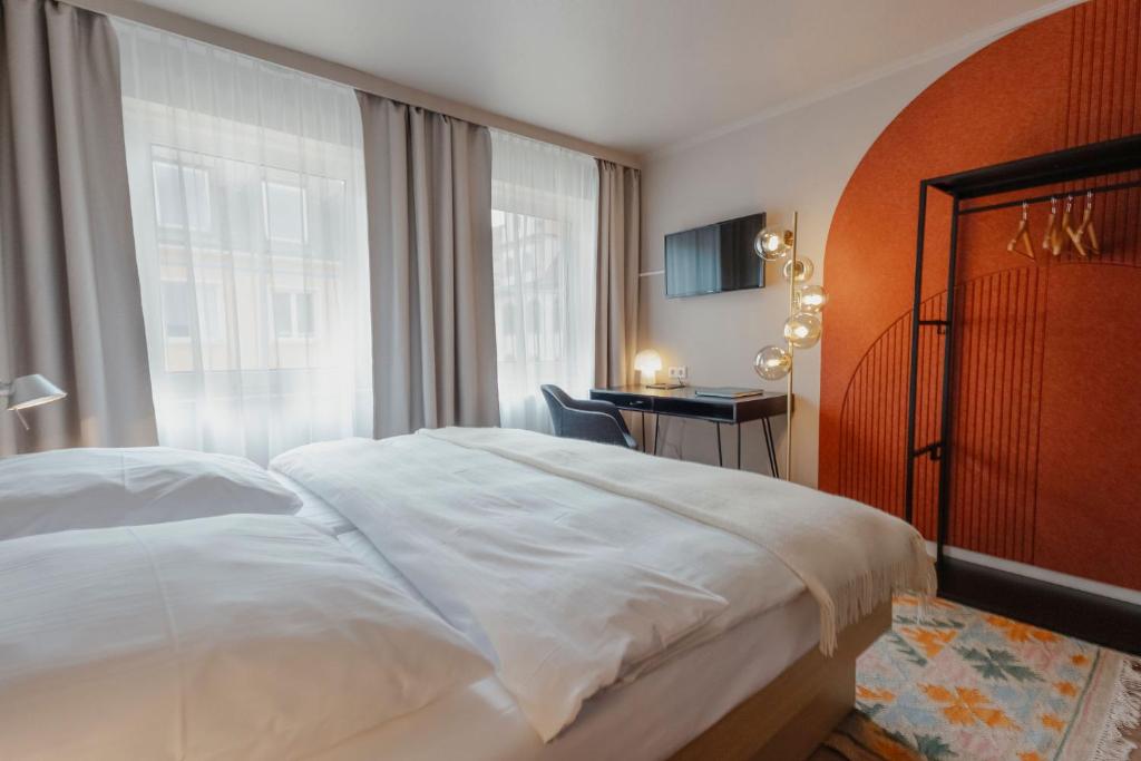 a bedroom with a white bed and a window at Hotel Lux in Munich