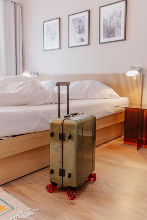 a suitcase is sitting in front of a bed at Hotel Lux in Munich