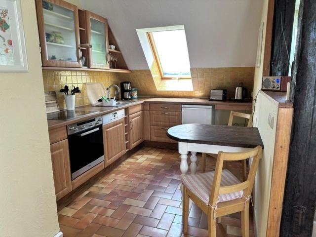 a kitchen with wooden cabinets and a table and a window at Landferienwohnung 1 Danneborth in Danneborth