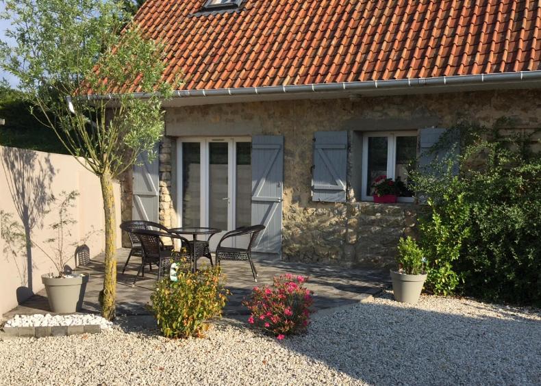 a patio of a house with a table and chairs at Petit gite cote opale in Colembert