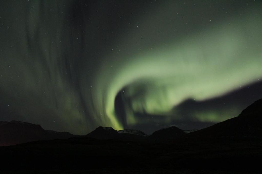 an aurora in the sky over a mountain at Studio 22 in Reyðarfjörður