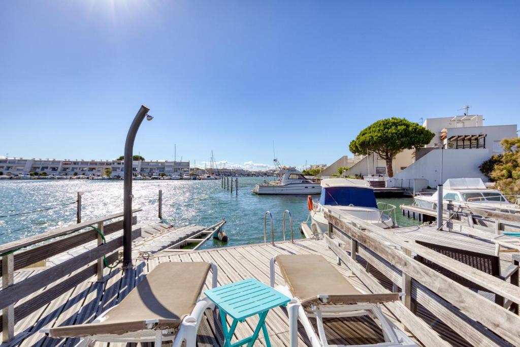 un quai avec des chaises et des bateaux dans l'eau dans l'établissement Marina Port Camargue, au Grau-du-Roi