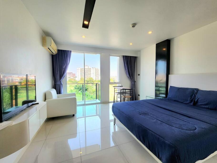 a bedroom with a blue bed and a large window at Nice studio comfortable in Pattaya Central