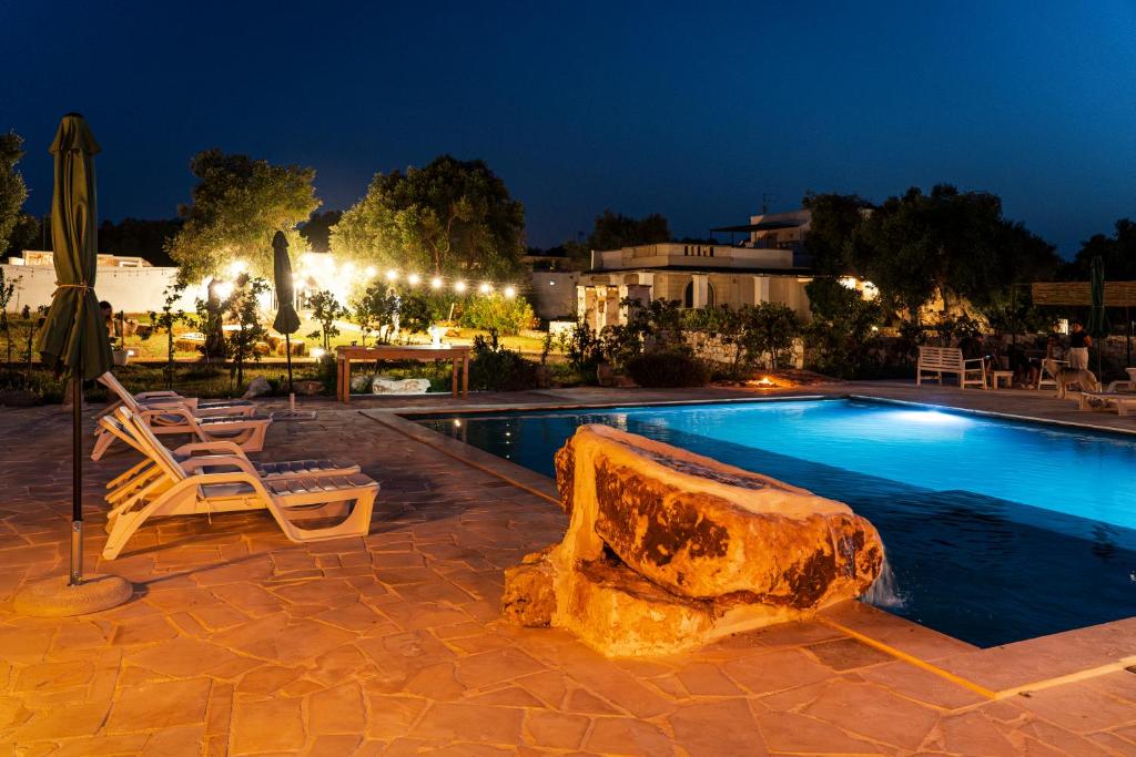 a pool with a lounge chair and a rock next to it at Masseria della Piana in Villanova di Ostuni