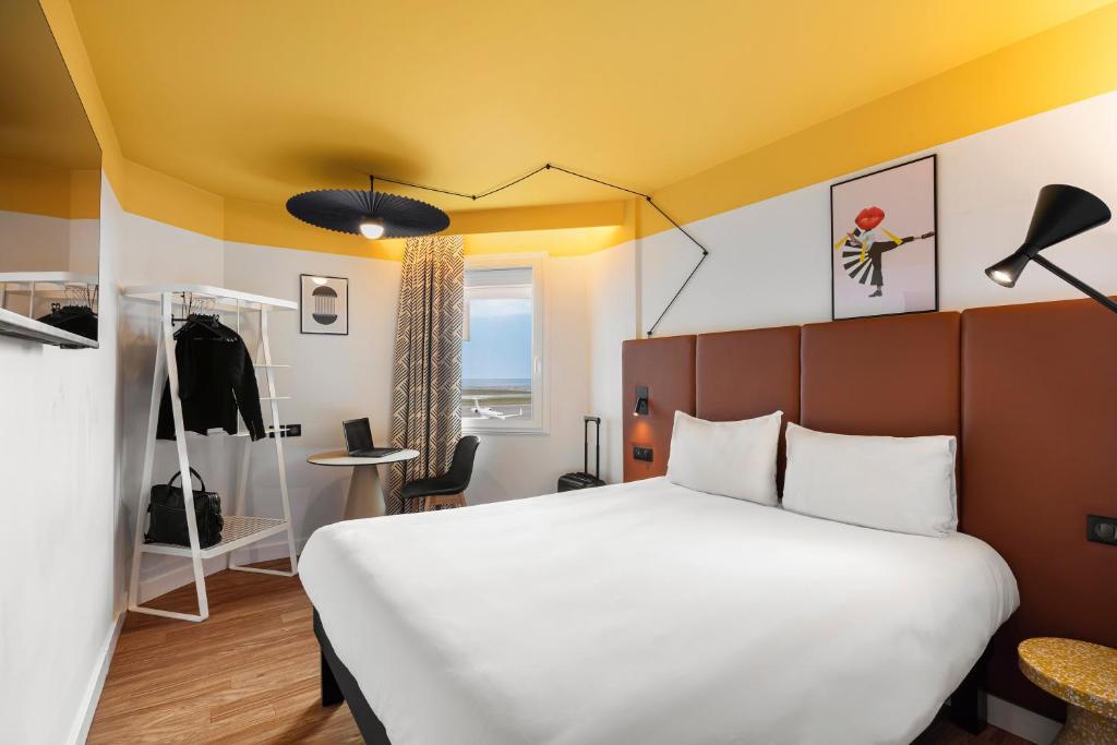 - une chambre avec un grand lit et un plafond jaune dans l'établissement ibis Nice Aéroport Promenade des Anglais, à Nice