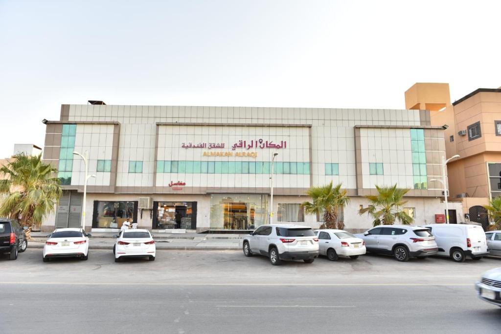 a building with cars parked in a parking lot at شقق المكان الراقي للشقق المخدمة in Riyadh