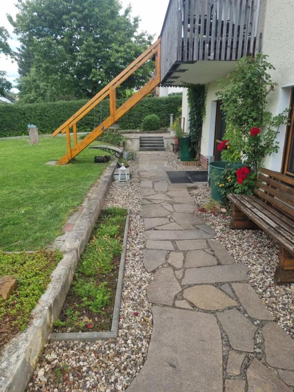 ein Steinweg, der zu einem Haus mit einer Holztreppe führt in der Unterkunft Ferienwohnung Tom in Schnaittenbach
